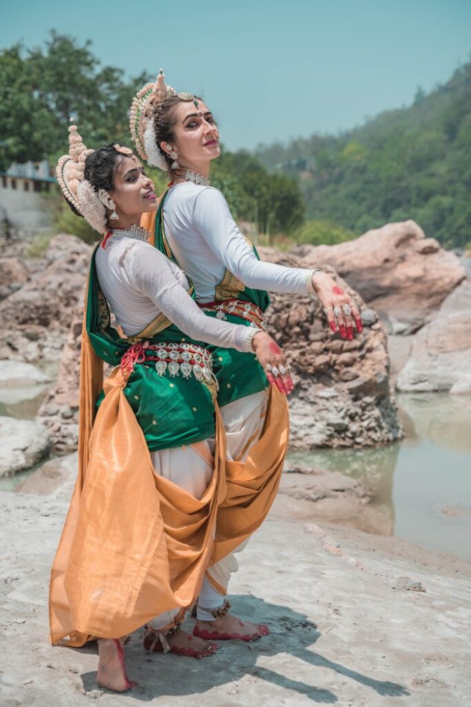 Elegant Odissi dancers strike poses outdoors, showcasing traditional Indian classical dance attire and expressions.