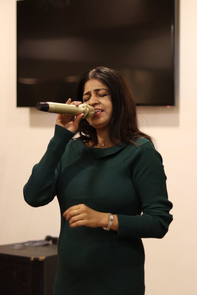 A woman passionately singing indoors, holding a microphone. Captures the essence of live music performance.