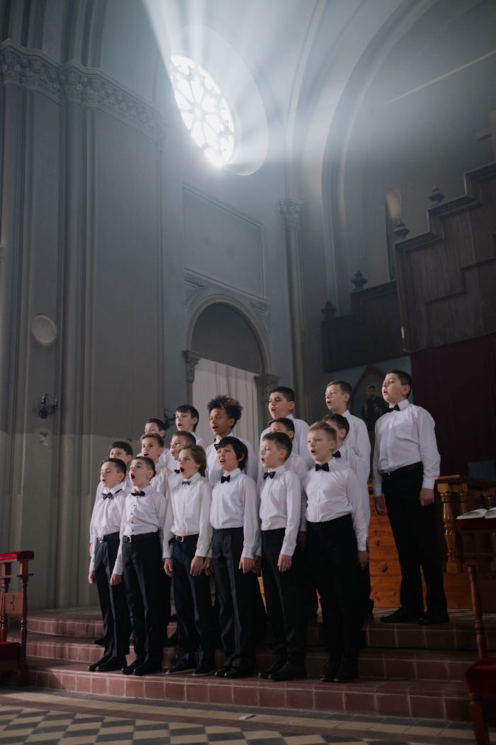 A diverse boys choir performing in unison under a dramatic light in a historic church.